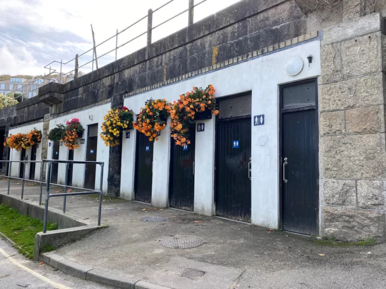 St Ives Cornwall Porthminster Toilets. A row of doors for public toilets and hanging baskets of flowers