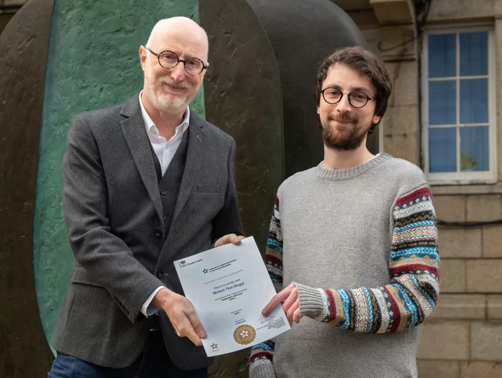 two men holding a certificate in front of Barbara Hepworth bronze scupture