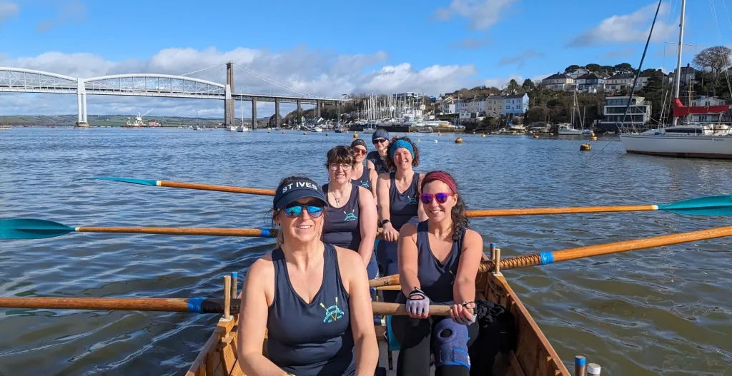 women in a gig boat holding oars