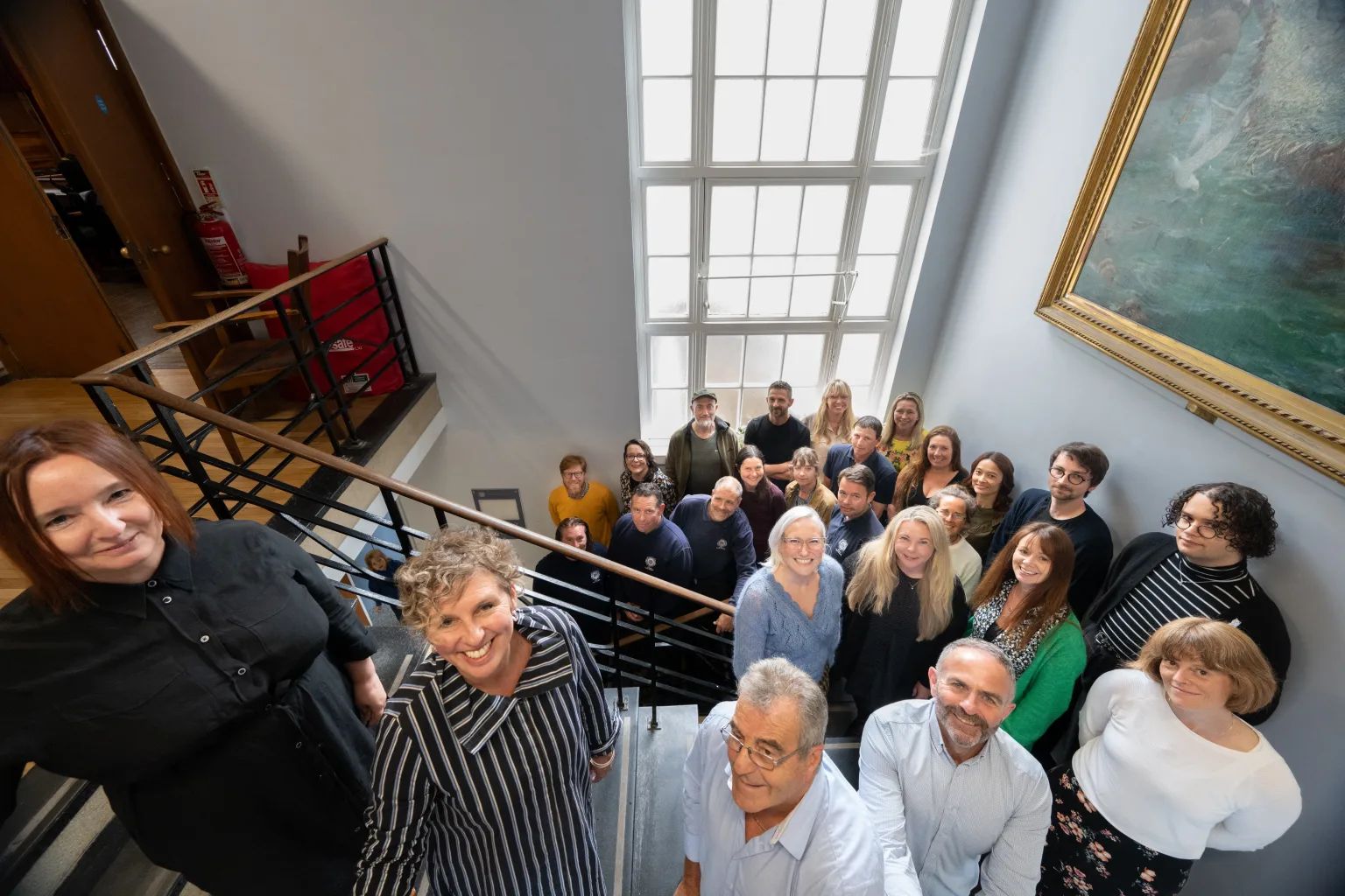 Group of people on stairs with a large window